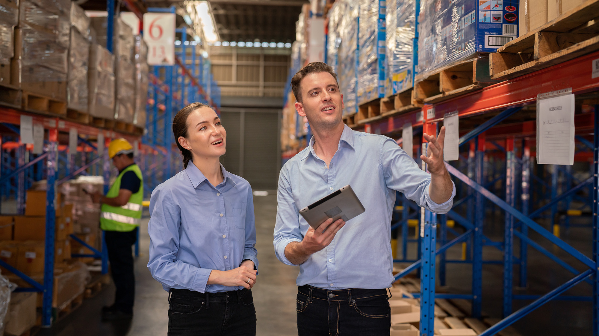 Warehouse employee and supplier reviewing manufacturing stock levels in a parts warehouse